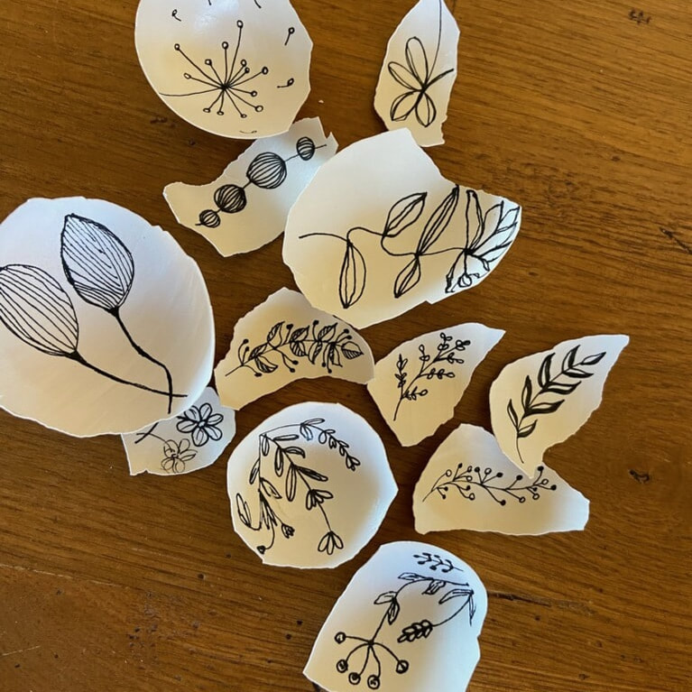 eggshells with thin black ink drawings of simple flowers inside